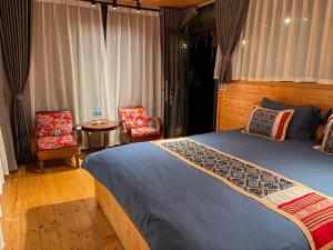 a bedroom with a bed and two chairs and a table at Son Bá Mười Ecolodge 