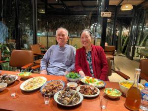 a man and woman sitting at a table with food at Son Bá Mười Ecolodge  +22 photos