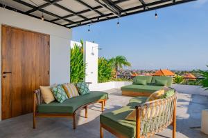 eine Terrasse mit zwei grünen Stühlen und einer Holztür in der Unterkunft Luxury 4BR Villa Private Pool & Sea Horizon in Kerobokan