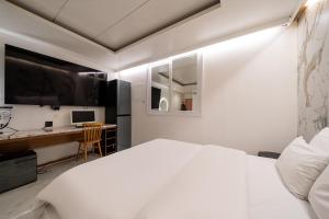 a bedroom with a white bed and a desk at S Hotel in Bucheon