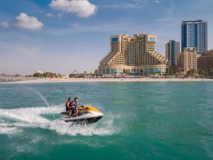 two people riding a speed boat in the water near a beach at Fairmont Ajman in Ajman 