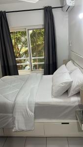 a white bed with a window in a bedroom at Modern Apartment - Work from Zanzibar (Fumba Town) in Dambani