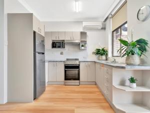 a kitchen with white cabinets and stainless steel appliances at Surf Beach Motel Coffs in Coffs Harbour
