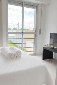 a white bedroom with a bed and a large window at Dpto GAMA a cuadras del corsodromo in Gualeguay