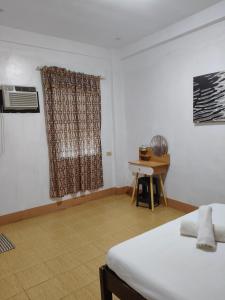a room with a bed and a window with a table at Touristlink Homestay in Donsol
