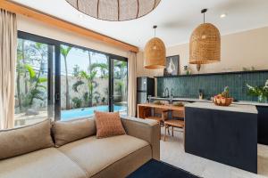 ein offenes Wohnzimmer mit Couch und Küche in der Unterkunft Stylish New Suites with Pool Near Balangan Beach in Bingin Beach