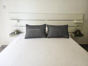 a bed with two black and white pillows on it at Modern Apartment - Work from Zanzibar (Fumba Town) in Dambani +103 photos