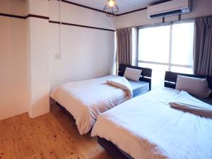a room with two beds and a window at Guesthouse Banvina in Kagoshima