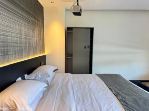 a bedroom with a bed with white sheets and pillows at The Panda Artisan, Taikoo Li Xilia Hotel in Chengdu +5 photos
