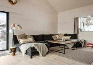ein Wohnzimmer mit einer schwarzen Couch und einem Tisch in der Unterkunft New Cabin With Panoramic Views At Hardangervidda in Maurset