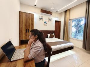 una mujer sentada en un escritorio con un ordenador portátil en un dormitorio en Hotel Ramayan Inn, en Rishīkesh