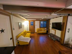 a living room with yellow couches and a flat screen tv at Entire ADU with hottub in Burien