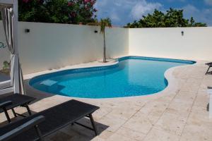 a swimming pool next to a white wall at WaraWara Mini resort in Jan Thiel