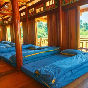 a row of blue beds in a room with windows at Bình Bản Liền Homestay - Vang A Binh in Bắc Hà
