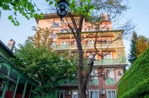 wysoki budynek z drzewem przed nim w obiekcie Prestige Palace - Esquisse Hotel w mieście Tbilisi City
