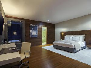 ein Schlafzimmer mit Bett, Schreibtisch und Waschbecken in der Unterkunft La Cigale Hotel Managed by Accor in Doha