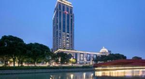 un edificio alto frente a un edificio grande en Hampton by Hilton Suzhou XiangCheng, en Suzhou
