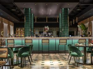 a restaurant with green chairs and tables and a bar at Habita79 Hotel Pompeii - MGallery Collection in Pompei