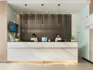 two women sitting at a counter in an office at Jinjiang Inn Select Xuzhou High-speed Railway Station Kunpeng Road in Xuzhou