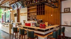Un restaurante con un bar con sillas verdes. en James Joyce Coffetel Chengdu Century City Convention and Exhibition Center, en Chengdú