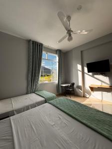 a bedroom with two beds and a flat screen tv at Los Bosques INN in San Ramón