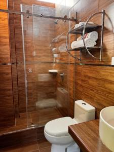 a bathroom with a toilet and a glass shower at Los Bosques INN in San Ramón