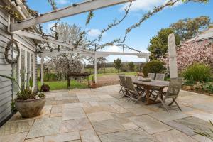 a patio with a wooden table and chairs at Hazeldene, charm & vines in Heathcote