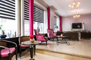 een woonkamer met roze stoelen en een televisie bij Hotel Corona Rodier in Parijs