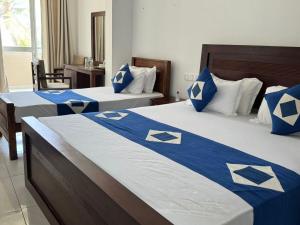 2 camas en una habitación de hotel con sábanas azules y blancas en Nico Beach Hotel, en Hikkaduwa 150 fotos más