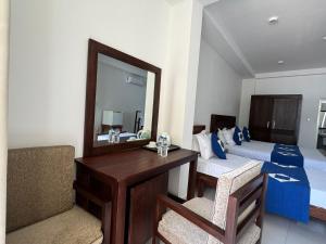 1 dormitorio con espejo, escritorio y cama en Nico Beach Hotel, en Hikkaduwa
