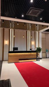 Un vestíbulo con una alfombra roja y un escritorio y una alfombra roja. en SUVON Hotel, en Stantsiya Kyzyl-Tukumachi