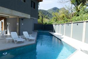 einen Pool mit Stühlen neben einem Gebäude in der Unterkunft Casaboa Paúba in São Sebastião