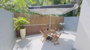 eine Terrasse mit Tisch und Stühlen und einem Sonnenschirm in der Unterkunft Casaboa Paúba in São Sebastião