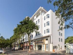 a white building on the side of a street at Jinjiang Metropolo Haikou East High Speed Railway Station Normal University in Haikou