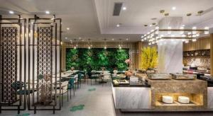 a restaurant with tables and chairs and a green wall at Jinjiang Metropolo Haikou East High Speed Railway Station Normal University in Haikou