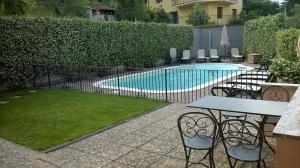 a fence with a table and chairs next to a swimming pool at La Spiaggia in Oliveto Lario