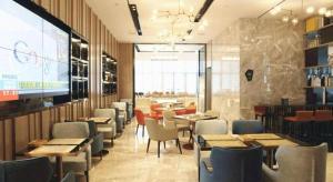 a restaurant with tables and chairs and a large screen at Echarm Hotel Wuhan High-speed Rail Peace Park Metro Station in Wuhan