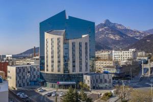 ein großes Glasgebäude mit Bergen im Hintergrund in der Unterkunft Echarm Hotel Tai'an Taishan Tianwai Village Hongmen in Tai'an