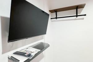 a shelf with a tv and a remote control at RedDoorz at Batam Center 3 in Pulau Sembakau Kecil +14 photos