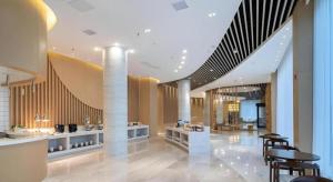 a lobby with tables and chairs in a building at Deep Sleep Hotel Xuzhou High-Speed Railway Station East Square Oubeisha in Xuzhou