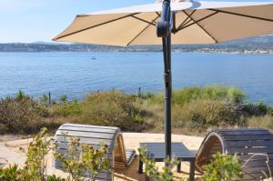 duas cadeiras e um guarda-sol junto à água em Villa Hippocampe em Sanary-sur-Mer
