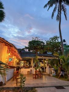 a man walking past a building with tables and chairs at Hotel Surf Resort in Arugam Bay