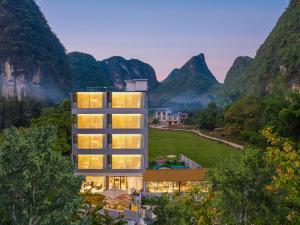 une vue d'un bâtiment avec des montagnes en arrière-plan dans l'établissement Yangshuo Soul Resort-Beside Yulong River, à Yangshuo