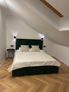 a bedroom with a large bed with a green headboard at Izabelės apartamentai in Palanga