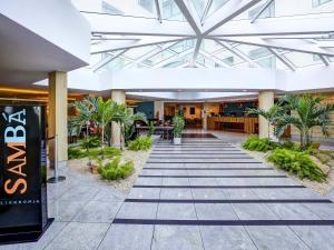 a hallway with palm trees in a building at Mercure Rio de Janeiro Barra da Tijuca in Rio de Janeiro