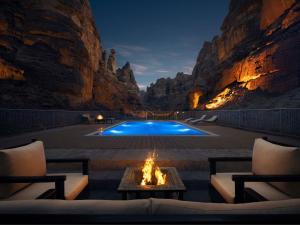 a patio with a fire pit and a swimming pool at Shaden Resort Al Ula, Managed by Accor in Al-ʿUla