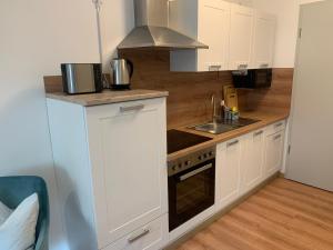 a kitchen with white cabinets and a sink and a stove at 1-Raum-Wohnung am Kurpark am Gradierwerk in Salzelmen