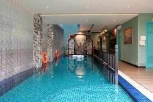a swimming pool with two orange chairs in a room at The An Bang Vanessa - Indochine Boutique Hotel in Hoi An