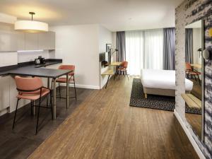 a kitchen and living room with a table and chairs at Aparthotel Adagio London Sutton Point in Sutton