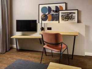 a desk with a computer monitor and a chair at Aparthotel Adagio London Sutton Point in Sutton